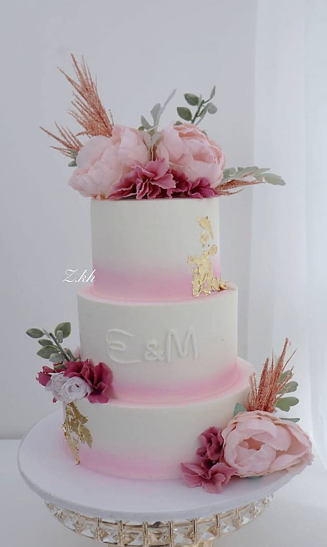 Three-tier pink ombre wedding cake with peonies, initials E & M